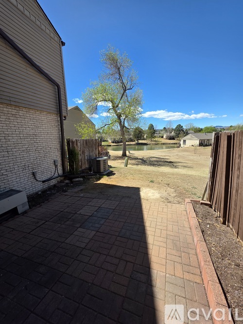 A backyard with a brick patio and a tree in the distance.