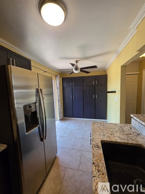 A kitchen with a stainless steel refrigerator and a fan on the ceiling.