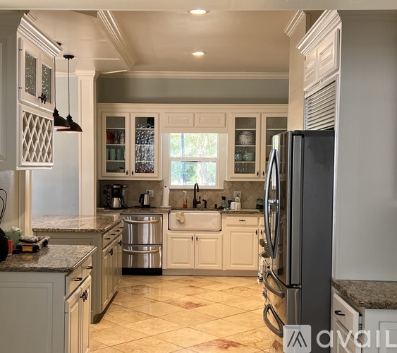 A kitchen with a black refrigerator and white cabinets.
