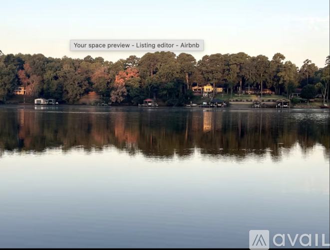 A serene lake with trees and buildings in the background.