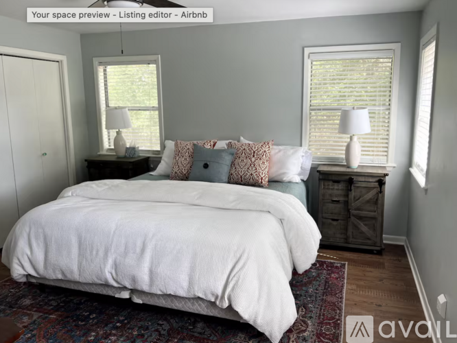 A bedroom with a white bed and a rug on the floor.