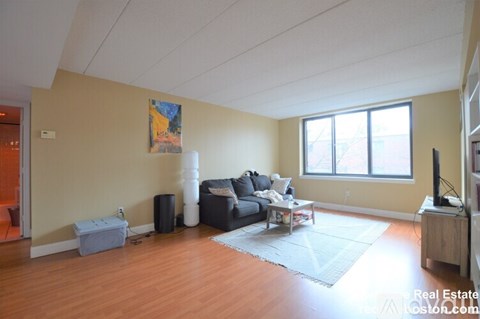 A living room with a grey couch and a painting on the wall.