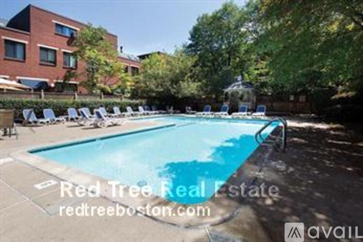 A pool with chairs around it and a building in the background.