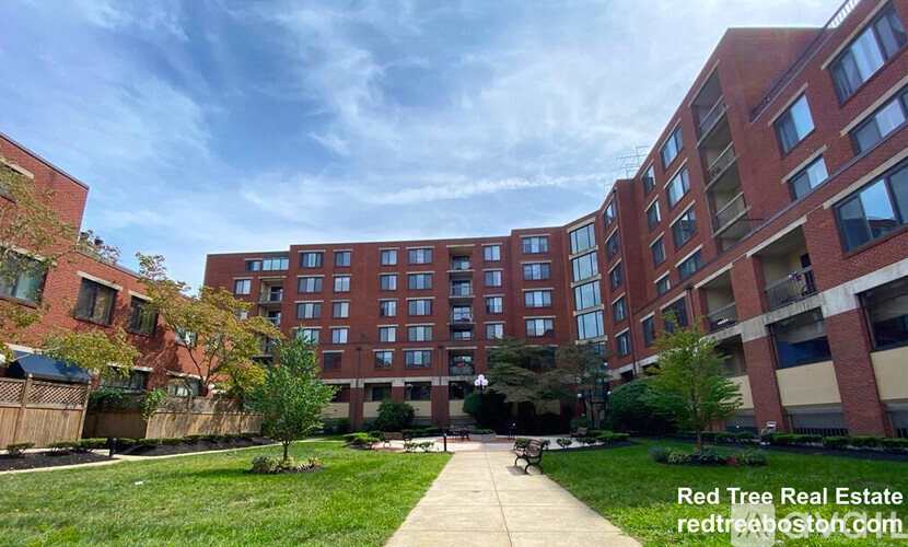 A large brick apartment complex with a walkway in the foreground.