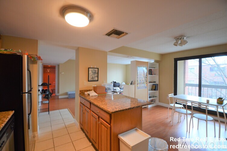 A kitchen with a refrigerator, sink, and dining table.