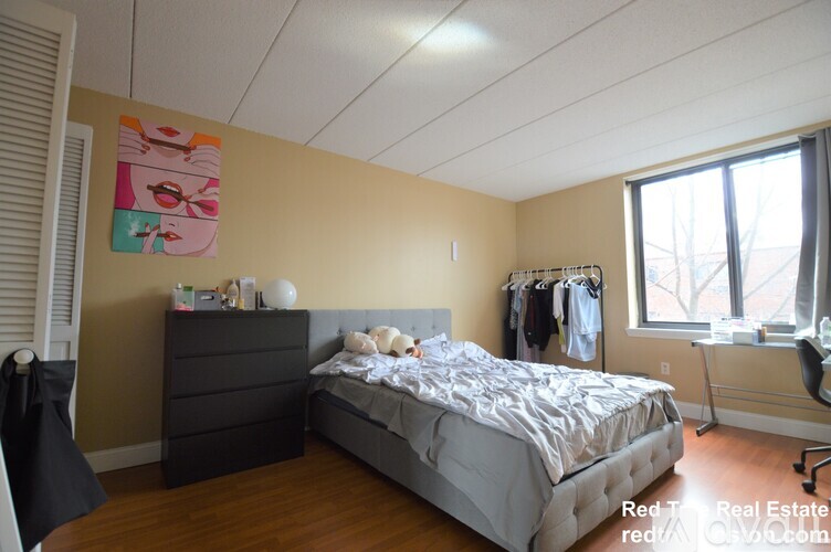 A bedroom with a bed, dresser, and window.