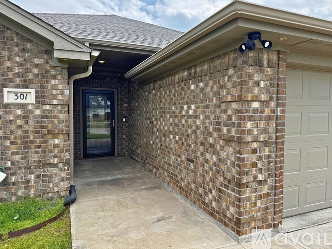 A brick house with a garage door and a number 301 on the wall.