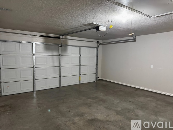 A spacious garage with a white wall and a grey floor.