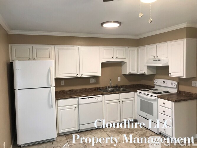 A kitchen with white appliances and brown countertops.