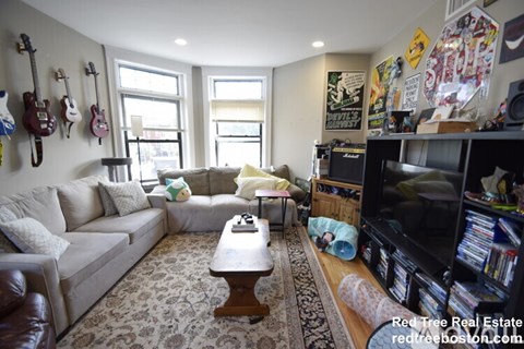 A living room with a couch, a coffee table, and a guitar wall.