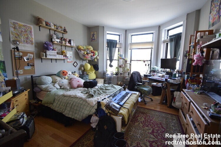 A messy bedroom with a bed in the center and a desk to the right.