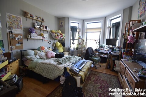 A messy bedroom with a bed in the center and a desk to the right.