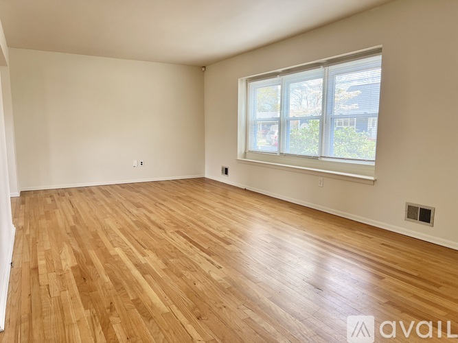 Empty room with wooden flooring and a window.