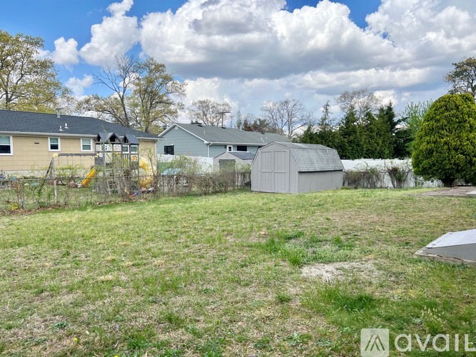 A grassy field with a shed and houses in the background.