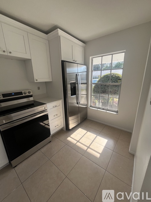 A kitchen with white cabinets and a stainless steel refrigerator.