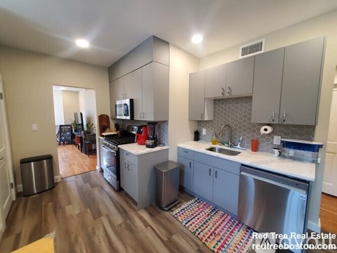 A kitchen with a sink, stove, and cabinets.