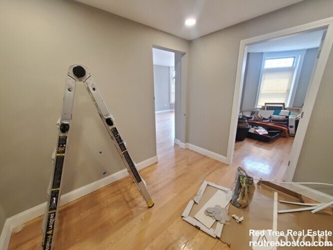 A room with a ladder and a broken picture frame on the floor.