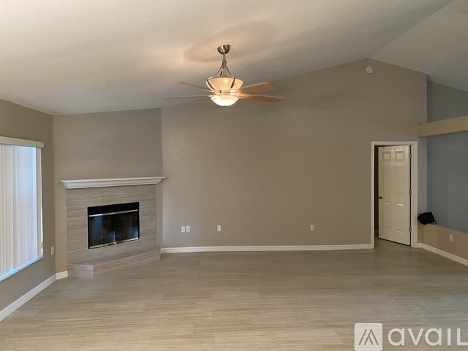 A spacious living room with a fireplace and a ceiling fan.