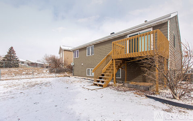 A house with a wooden deck in the snow.