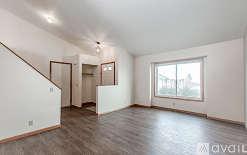 A spacious room with a window and a door leading to another room.