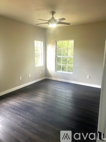 A room with a ceiling fan and two windows.