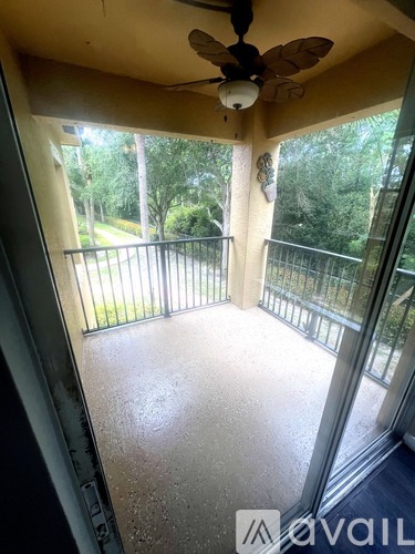 A balcony with a fan and a view of trees.