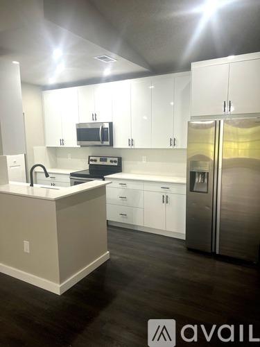 A kitchen with white cabinets and a stainless steel refrigerator.
