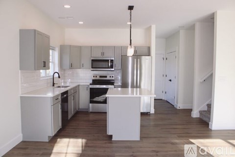 A modern kitchen with white cabinets and a wooden floor.
