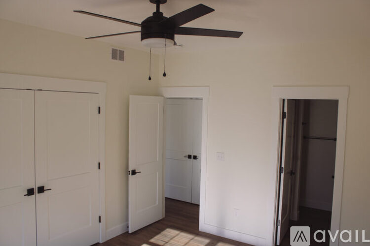 A room with a ceiling fan and white doors.