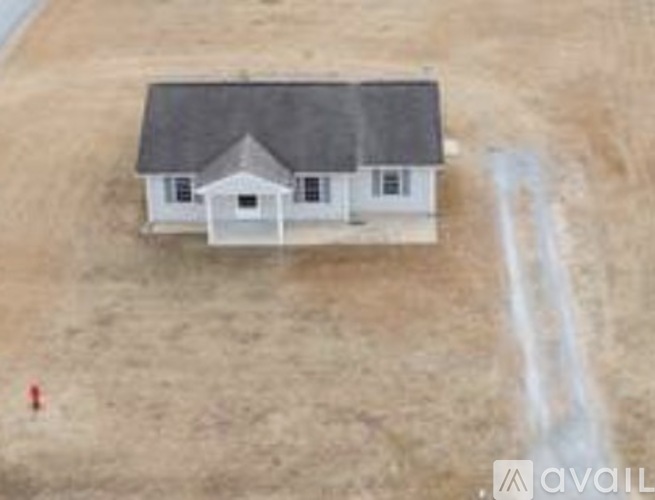 A house with a grey roof is situated in a field.