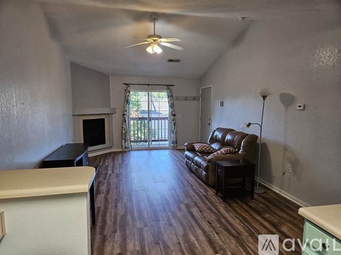 A living room with a brown leather couch and a ceiling fan.