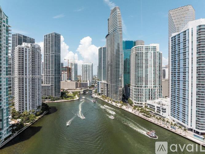 A cityscape with tall buildings and a river with boats.