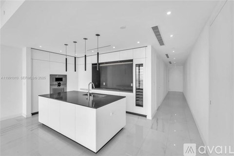 A modern kitchen with a central island and pendant lights.