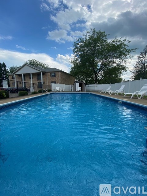 A swimming pool in front of a house with a cloudy sky.