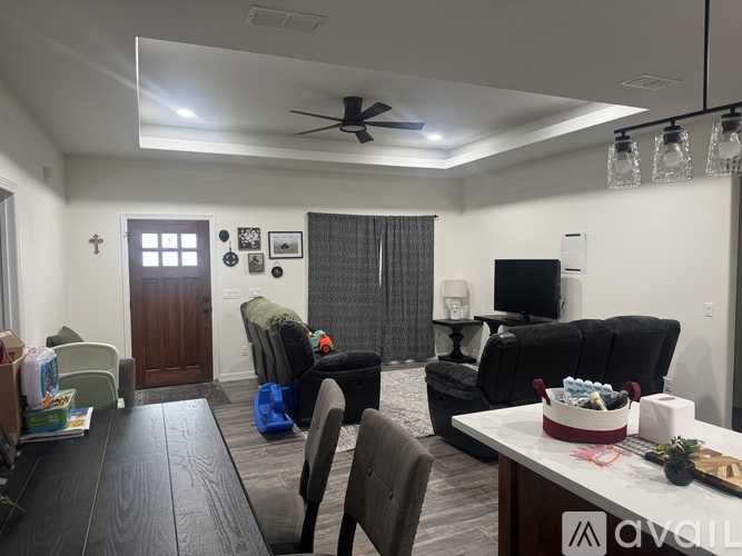 A living room with a black couch, a wooden table, and a ceiling fan.