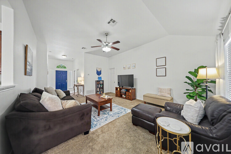 A living room with a brown couch and a ceiling fan.