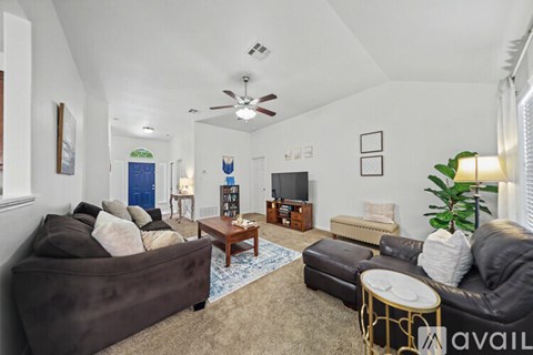 A living room with a brown couch and a ceiling fan.