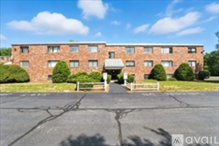 A brick building with a white roof and a sign that says "AVAIL" in front of it.