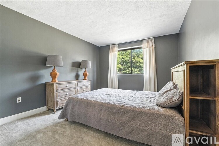 A bedroom with a bed, two nightstands with lamps, and a wooden bookcase.