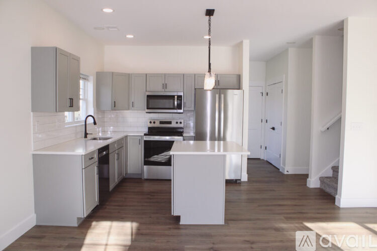 A modern kitchen with white cabinets and a wooden floor.