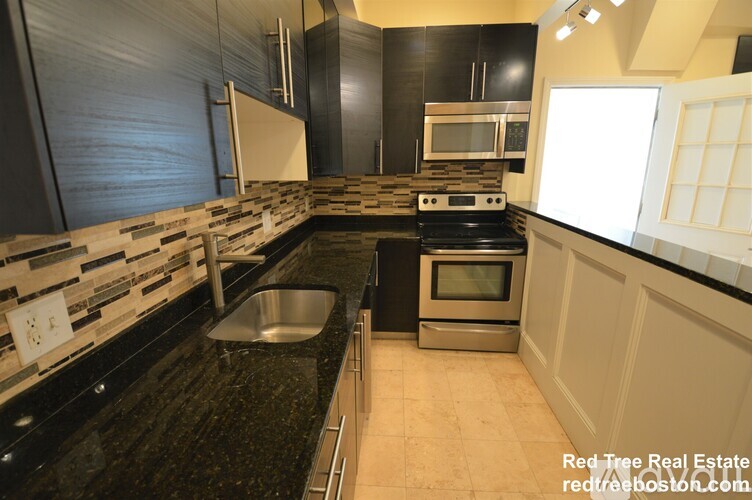 A modern kitchen with black granite countertops and stainless steel appliances.