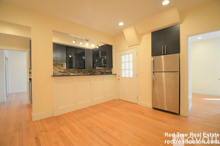 A kitchen with a refrigerator, cabinets, and a countertop.