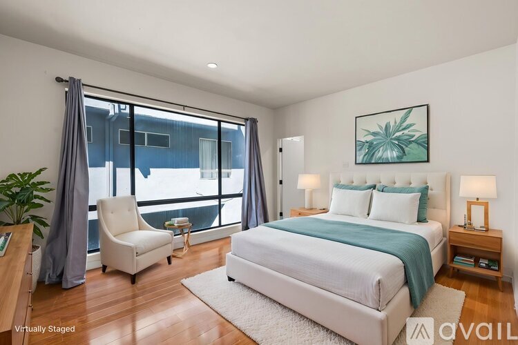 A bedroom with a large bed and a chair by the window.