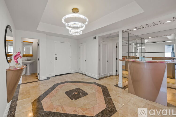 A well-lit, spacious bathroom with a marble floor and a vanity with a mirror.