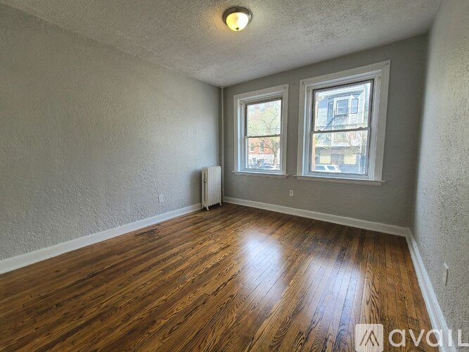 A room with wooden floors and two windows.