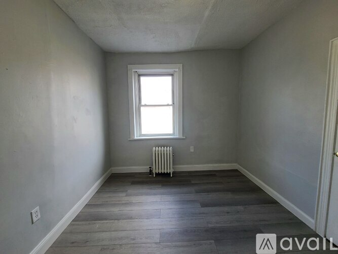 A room with a window and a radiator on the floor.