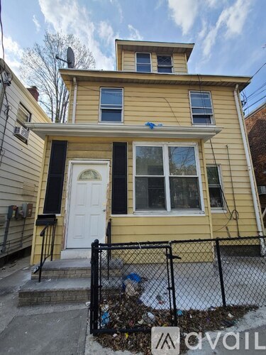 A yellow house with a black fence in front.