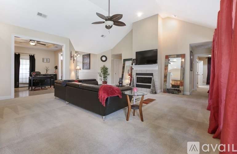 A spacious living room with a black sofa and a red throw blanket.