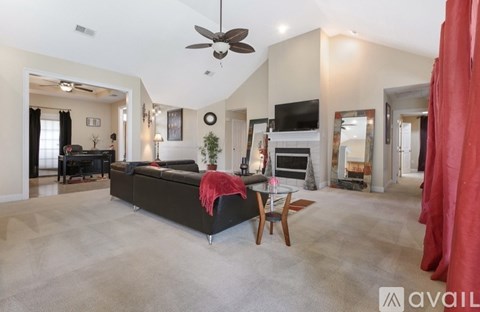 A spacious living room with a black sofa and a red throw blanket.