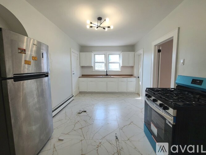 A kitchen with a stainless steel refrigerator, a black stove, and white cabinets.